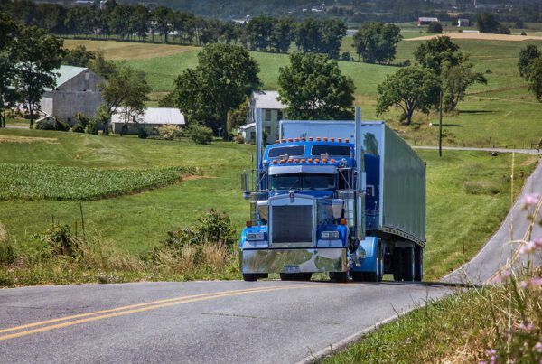 Insurance Solutions - Blue Tractor Trailer Truck Driving Up a Country Road on a Sunny Day